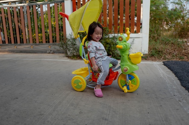 Photo une fille souriante assise sur un tricycle sur un sentier.