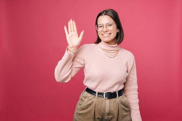 Une fille souriante aux cheveux courts portant des lunettes fait signe à la caméra