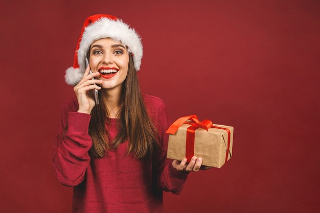 Fille souriante avec des cadeaux de Noël appelant au téléphone