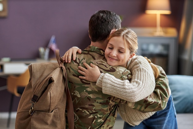 Fille souriante étreignant son père revenant de l'armée