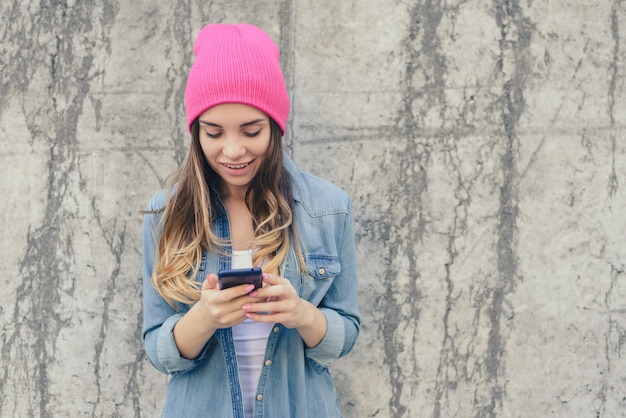 Fille souriante avec fond de mur gris smartphone