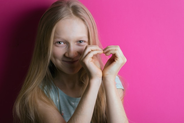 Une fille souriante a joint les mains en forme de coeur