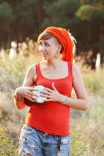 Fille souriante lumineuse avec jembe dans la forêt à l'extérieur