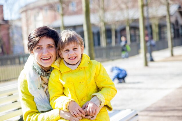 Fille souriante et maman dans le parc à pied assis sur un banc