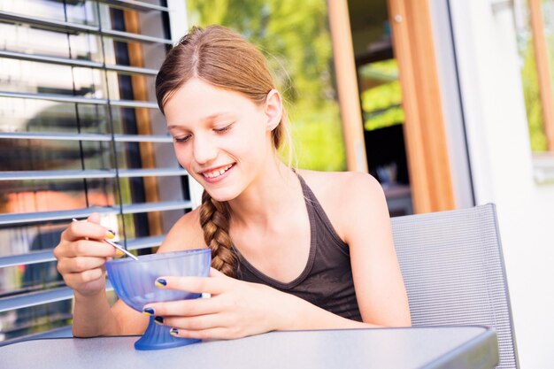 Une fille souriante mangeant au restaurant.