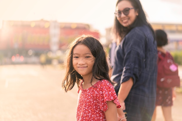 Fille souriante marchant avec sa mère au coucher ou au lever du soleil