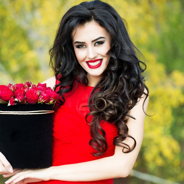 Fille souriante sexy avec des roses rouges