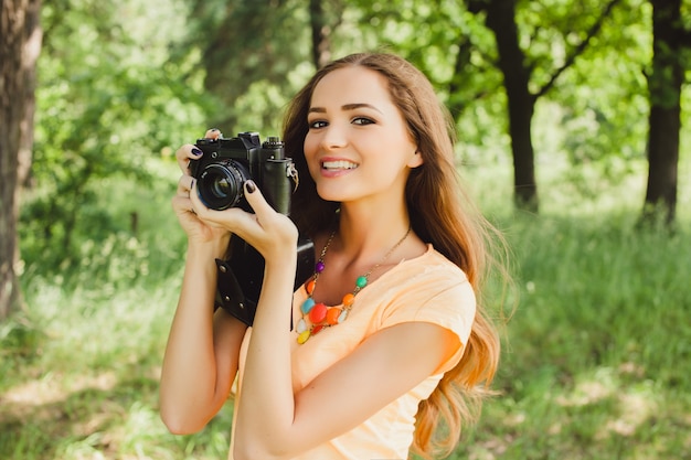 Fille souriante tenant un appareil photo avec ses mains