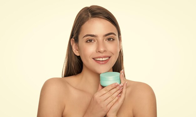 Une fille souriante tient un masque capillaire avec une crème pour la peau, une habitude quotidienne et des soins personnels