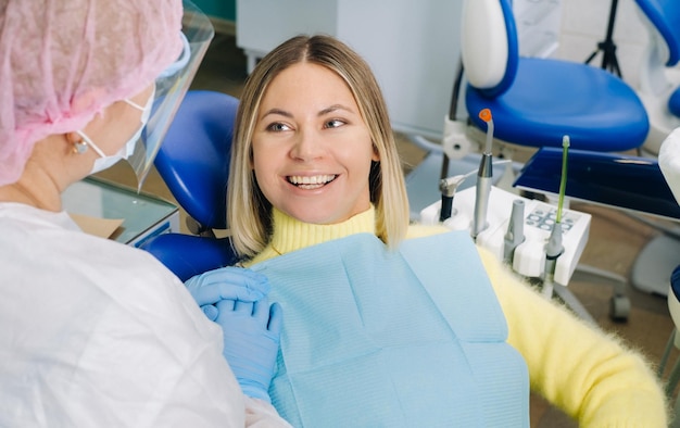 La fille sourit au dentiste et la regarde