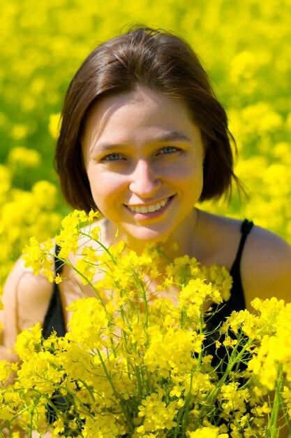 une fille sourit dans un champ jaune en été