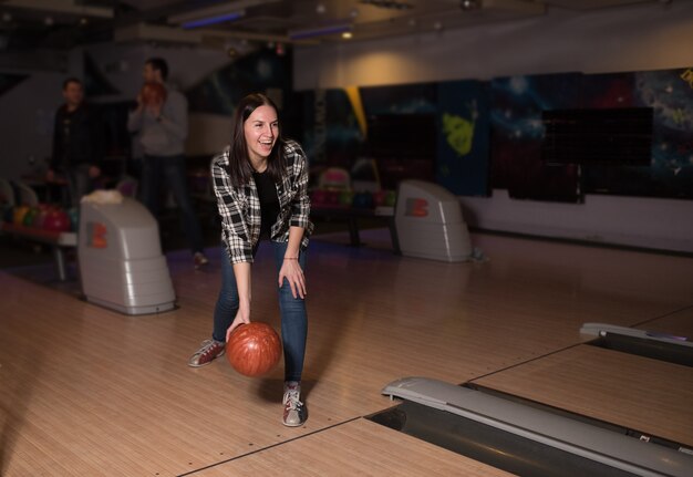 La fille sourit et joue dans le club de bowling