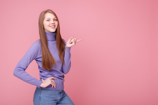 Fille sourit et montre de côté sur le fond