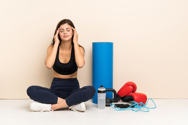 Fille de sport adolescent assis sur le sol avec mal de tête