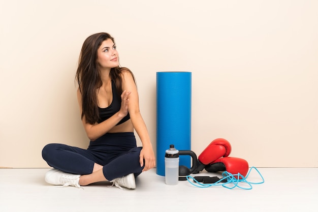 Fille de sport adolescent assis sur le sol en pensant à une idée