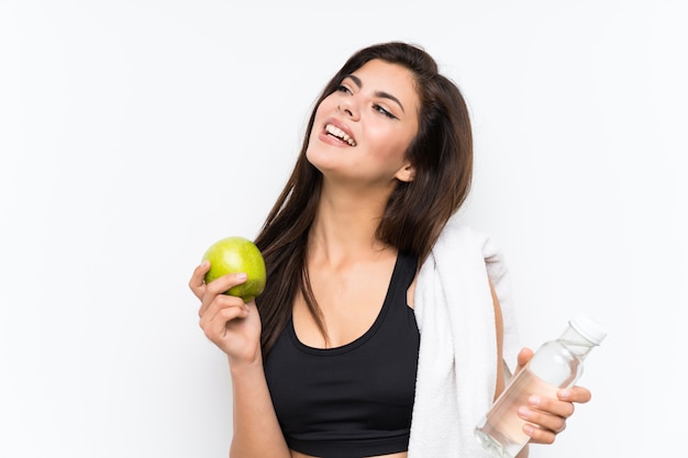 Fille de sport adolescent sur fond blanc isolé avec une pomme et une bouteille d'eau