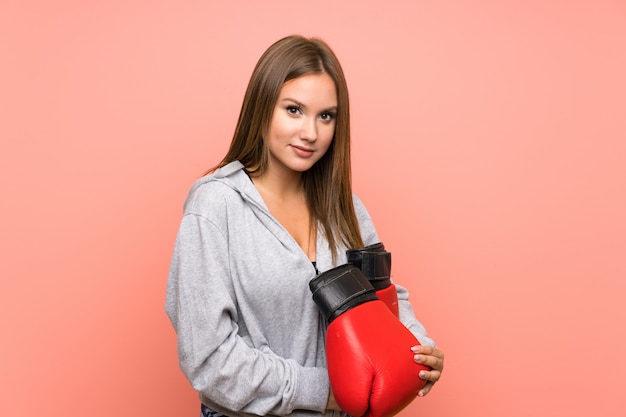 Fille de sport adolescent avec des gants de boxe sur mur rose isolé