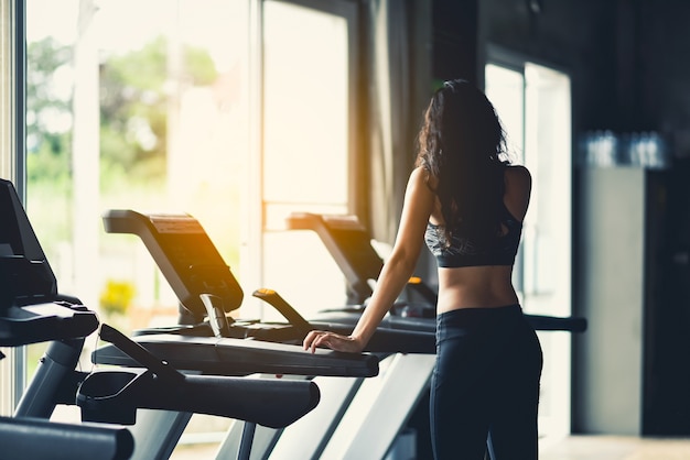 fille de sport debout sur le tapis roulant dans la salle de gym