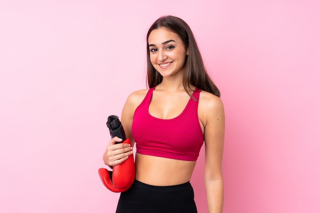 Fille de sport jeune sur fond rose isolé avec des gants de boxe