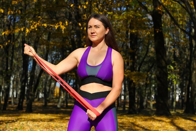 Fille sportive, faire des exercices avec un élastique de remise en forme dans le parc