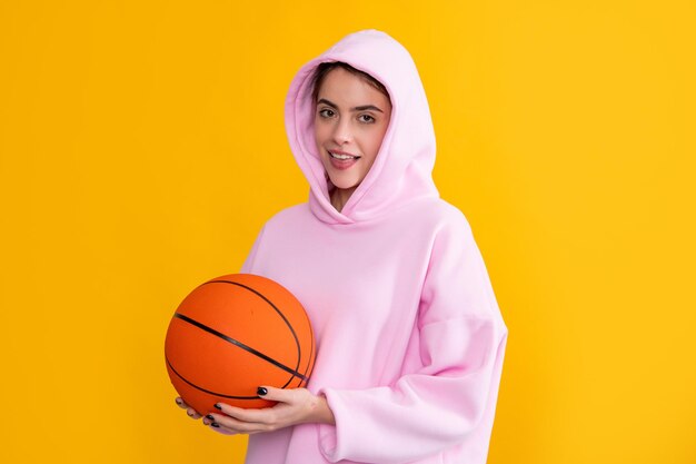 Fille sportive joyeuse avec ballon de basket sur fond jaune