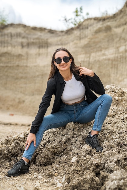 Fille sportive mince dans des vêtements décontractés posant contre les rochers de sable en été de carrière