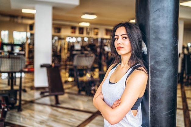 Fille sportive près du sac de boxe dans le gymnase