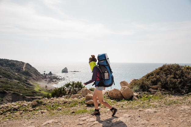 Fille sportive qui marche avec un sac à dos de randonnée et colle un masque spécial contre la poussière