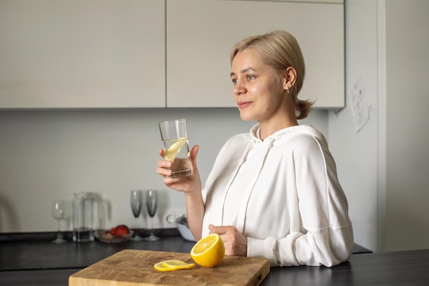 Une fille sportive tient un verre d'eau et de citron dans la cuisine