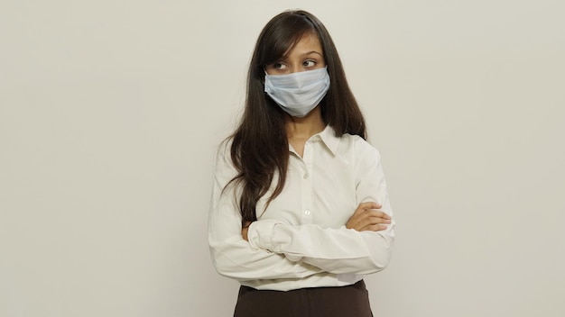 Photo une fille stricte et confiante croise les mains, interdit d'aller marcher dans l'air, porte un masque médical blanc