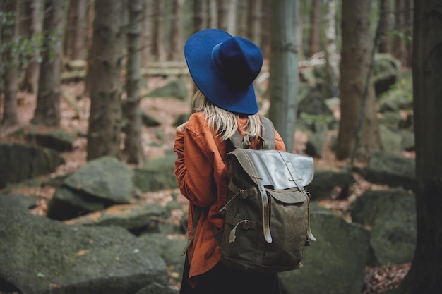 Fille de style au chapeau avec sac à dos dans une forêt de conifères mixte de l'heure d'été