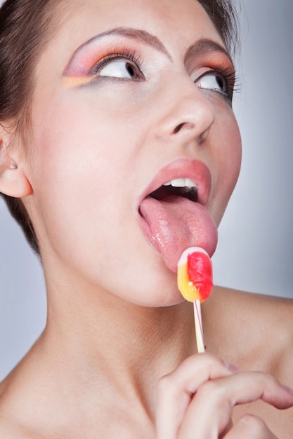 La fille avec un sucre candi. La belle jeune fille lèche un sucre candi.