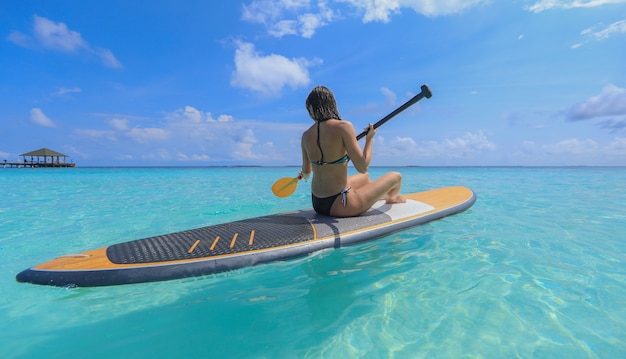 Fille de surf SUP aux Maldives