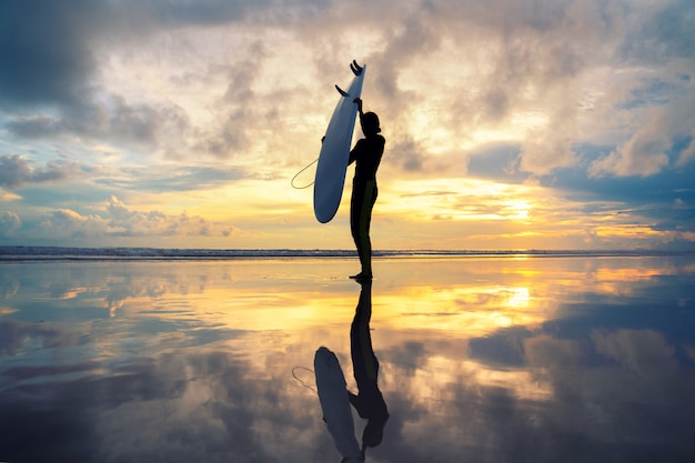 Photo fille de surfeur surfant au coucher du soleil sur la plage de l'océan