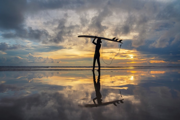 Fille de surfeur surfant au coucher du soleil sur la plage de l&#39;océan