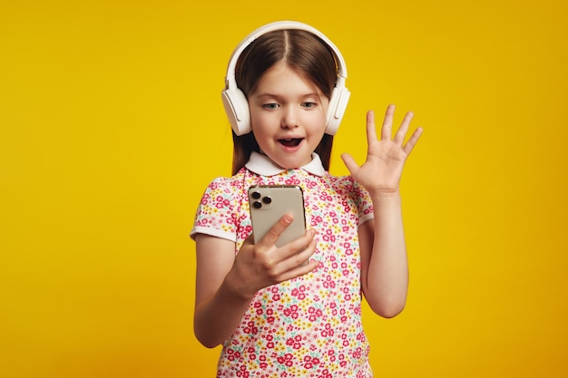 Une fille surprise dans les écouteurs tient le téléphone heureux de recevoir une notification