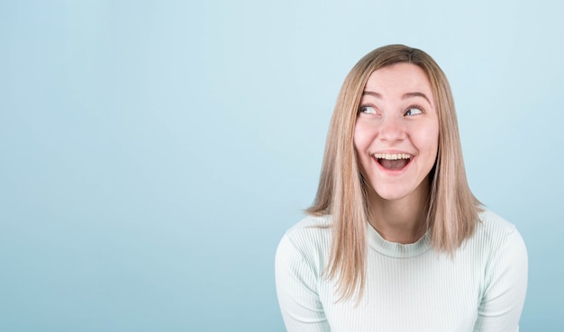 Fille surprise dans un haut bleu sur un mur bleu