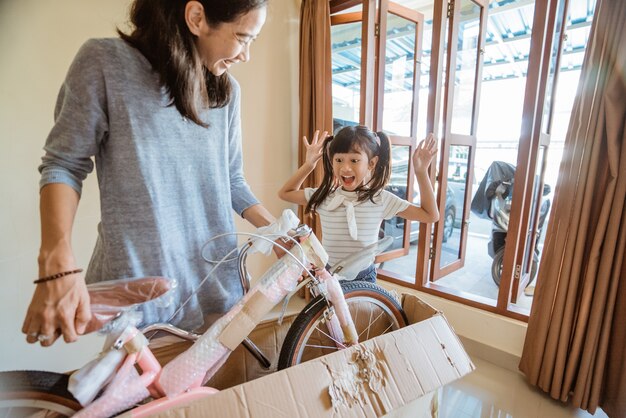 Fille surprise en déballant avec sa mère un nouveau mini vélo