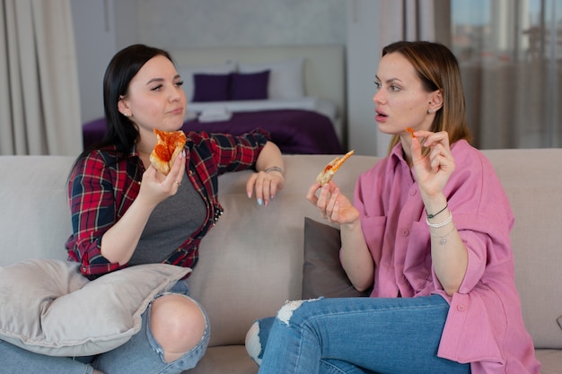 Une fille surprise raconte l'histoire de sa petite amie qui mange ensemble une délicieuse pizza photo de haute qualité