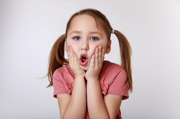 Fille avec surprise souffrant de maux de dents tenant sa joue