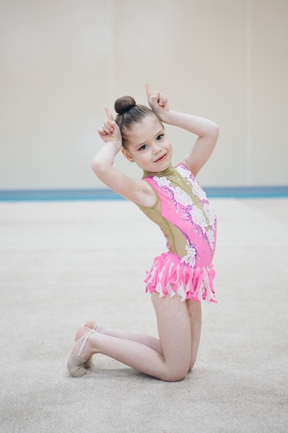 Une fille en survêtement fait un étirement. La gymnaste fait du sport. Concept de mode de vie sain, uniformes de sport, coupe du monde, gymnase, vêtements spécialisés, uniformes