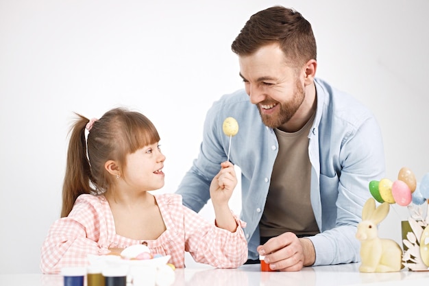 Fille avec le syndrome de Down et son père jouant avec des oeufs de Pâques colorés