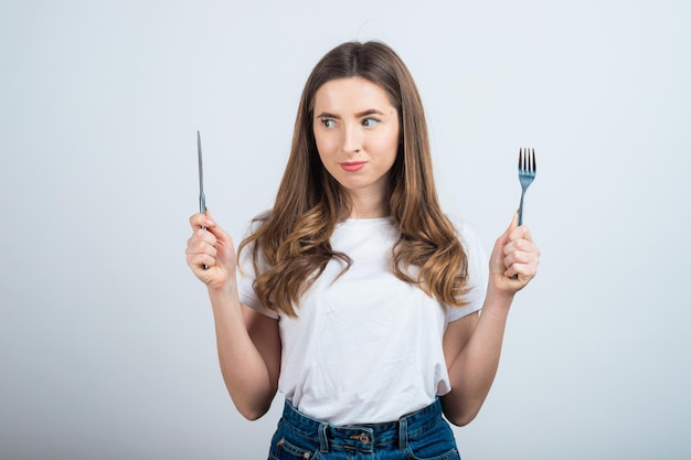 une fille en t-shirt blanc tient un bol de salade dans ses mains et mange