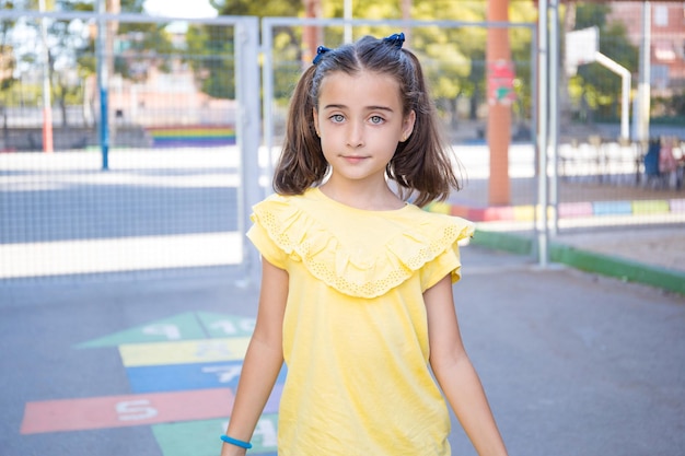 Fille en t-shirt jaune et deux nattes, posant face à la caméra, avec le jeu de sauter sur un l