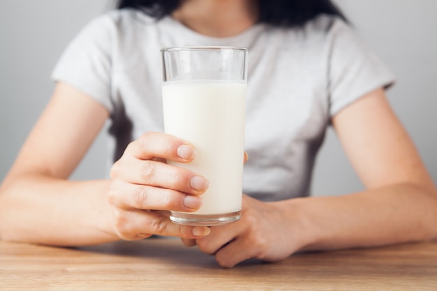 La fille à la table tient un verre de lait