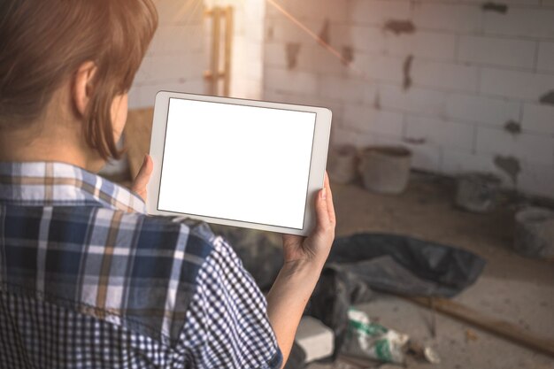 Fille avec une tablette devant une maison inachevée, réparation, concept de construction, photo de l'espace de copie