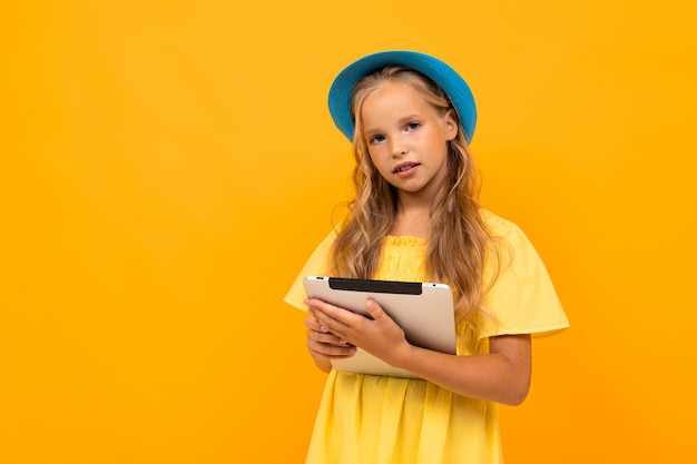 Photo fille avec une tablette sur un mur jaune