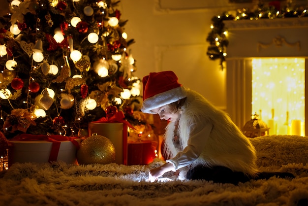 Fille avec tablette près de sapin de Noël