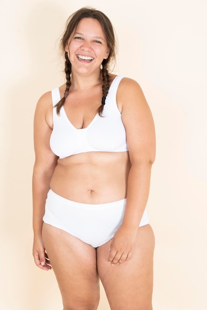 Fille de taille plus en lingerie avec deux tresses souriant et exhibant son corps fier de son corps