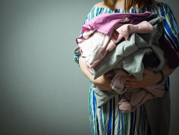 Fille avec un tas de linge sur fond gris